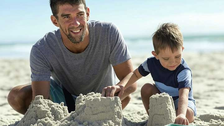 Phelps shares a joyful beach moment with family, showing calm liveliness and balanced energy.